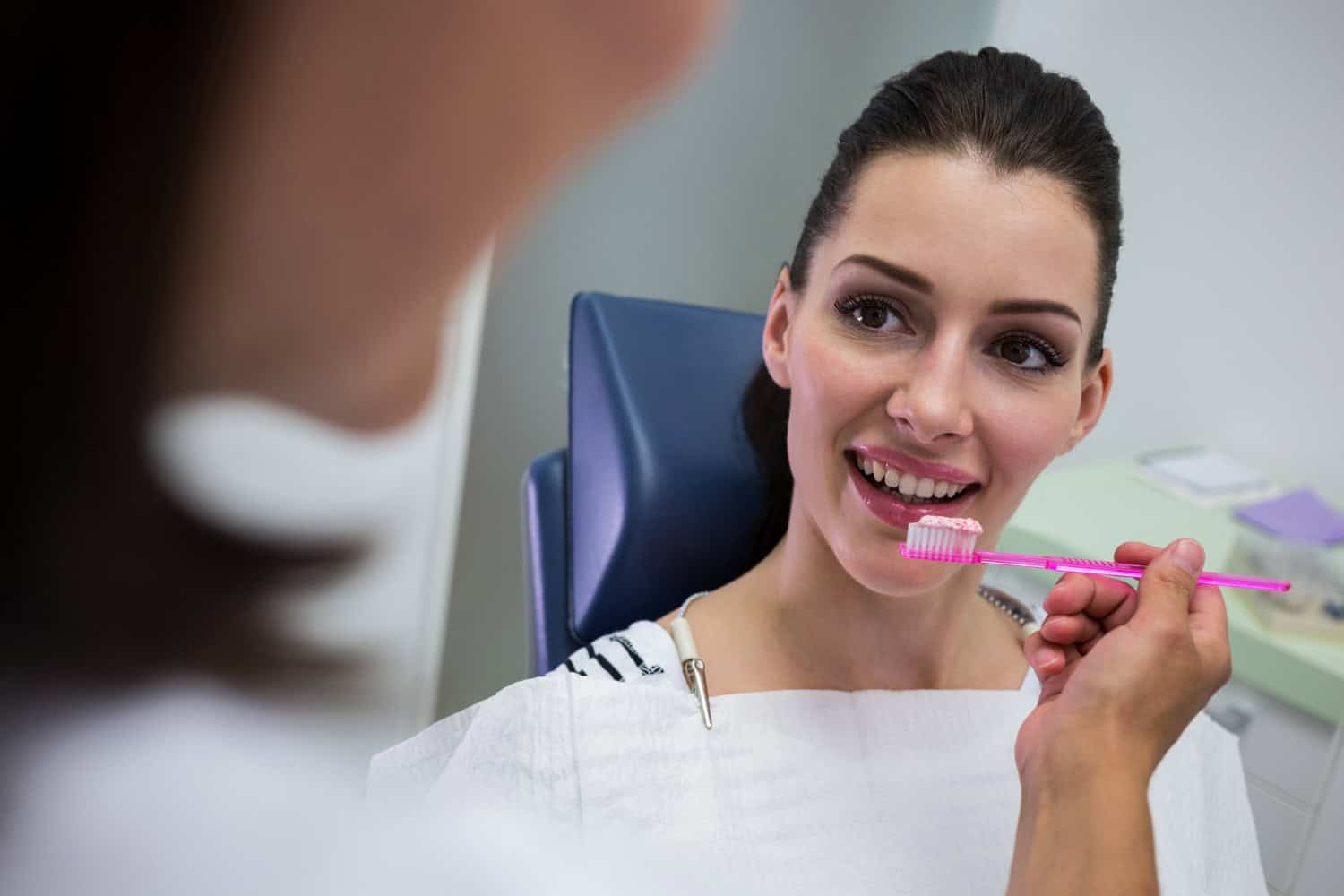 Dental implant care tips with a dentist demonstrating proper brushing techniques after dental implant treatment.