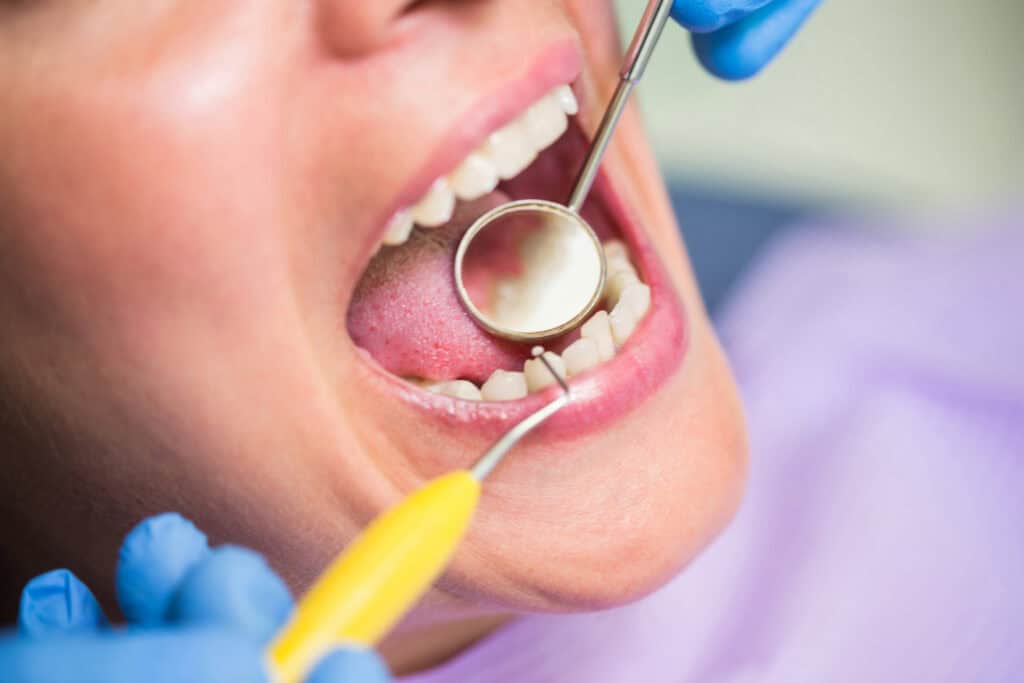 Dentist performing an oral examination before dental implant treatment to assess teeth and gum health in Reading, MA.