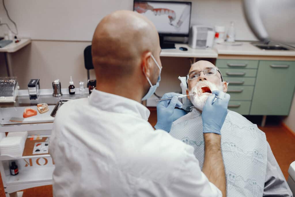 Dentist examining an older patient’s teeth during a routine dental checkup in a modern dental clinic.