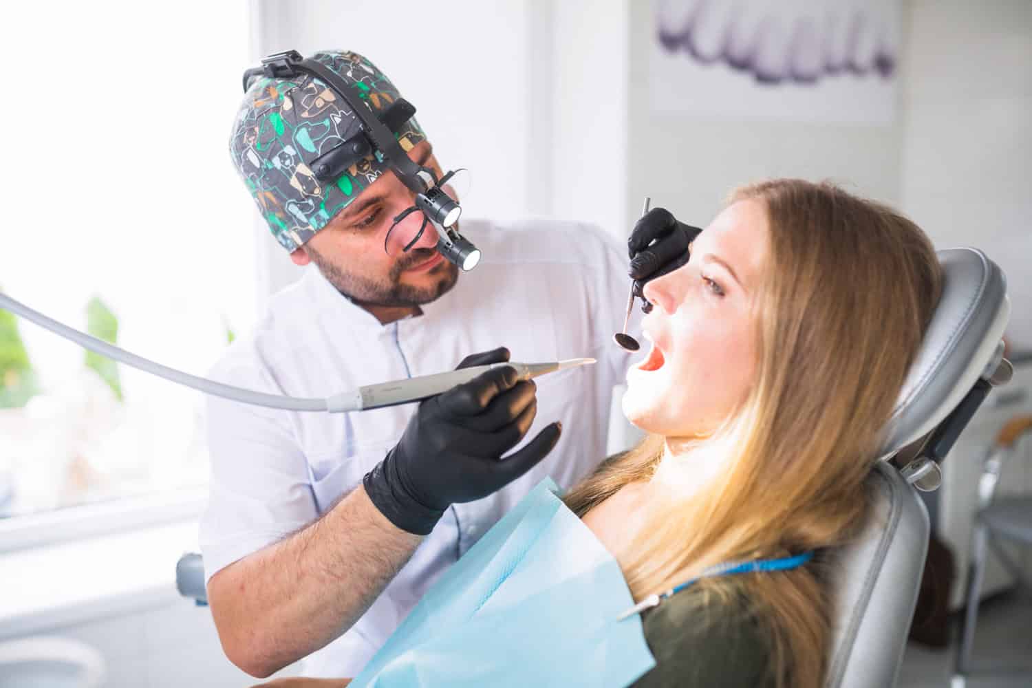 Dentist examining a patient's teeth during a restorative dental consultation to determine if a crown or filling is needed.