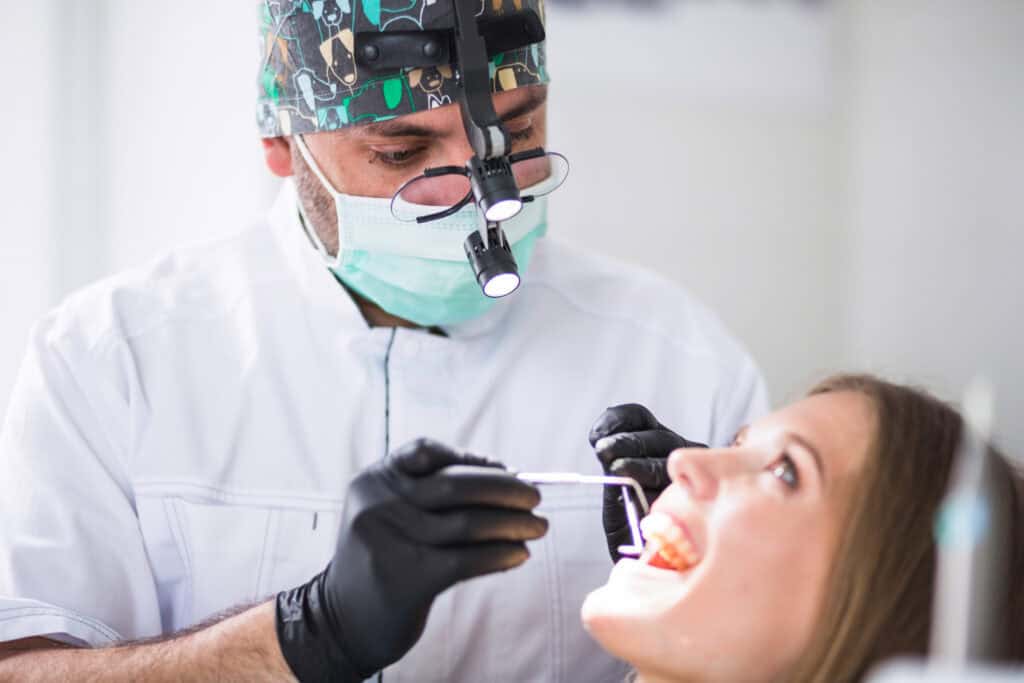 Dentist examining a patient’s teeth during root canal treatment and dental care.