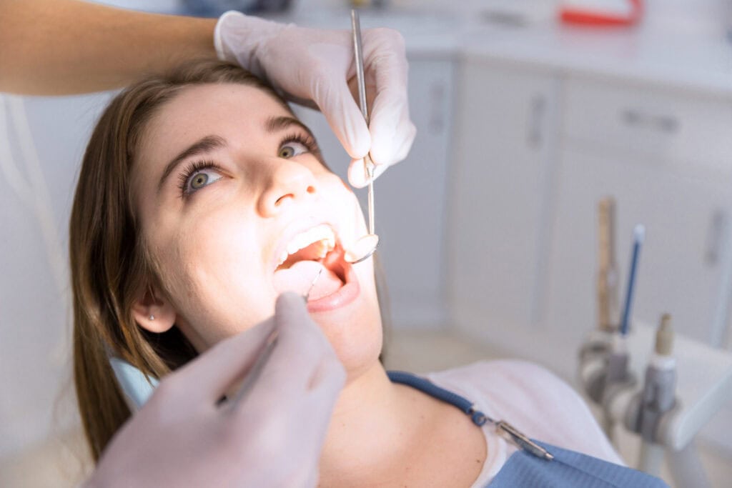 "Dentist performing a dental examination before evaluating a patient for a dental crown treatment in a modern dental office.
