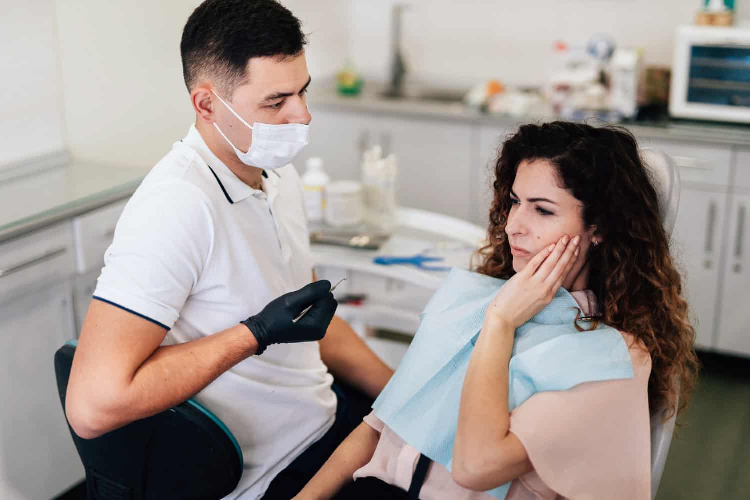 Dentist discussing tooth pain with a patient during a dental consultation.