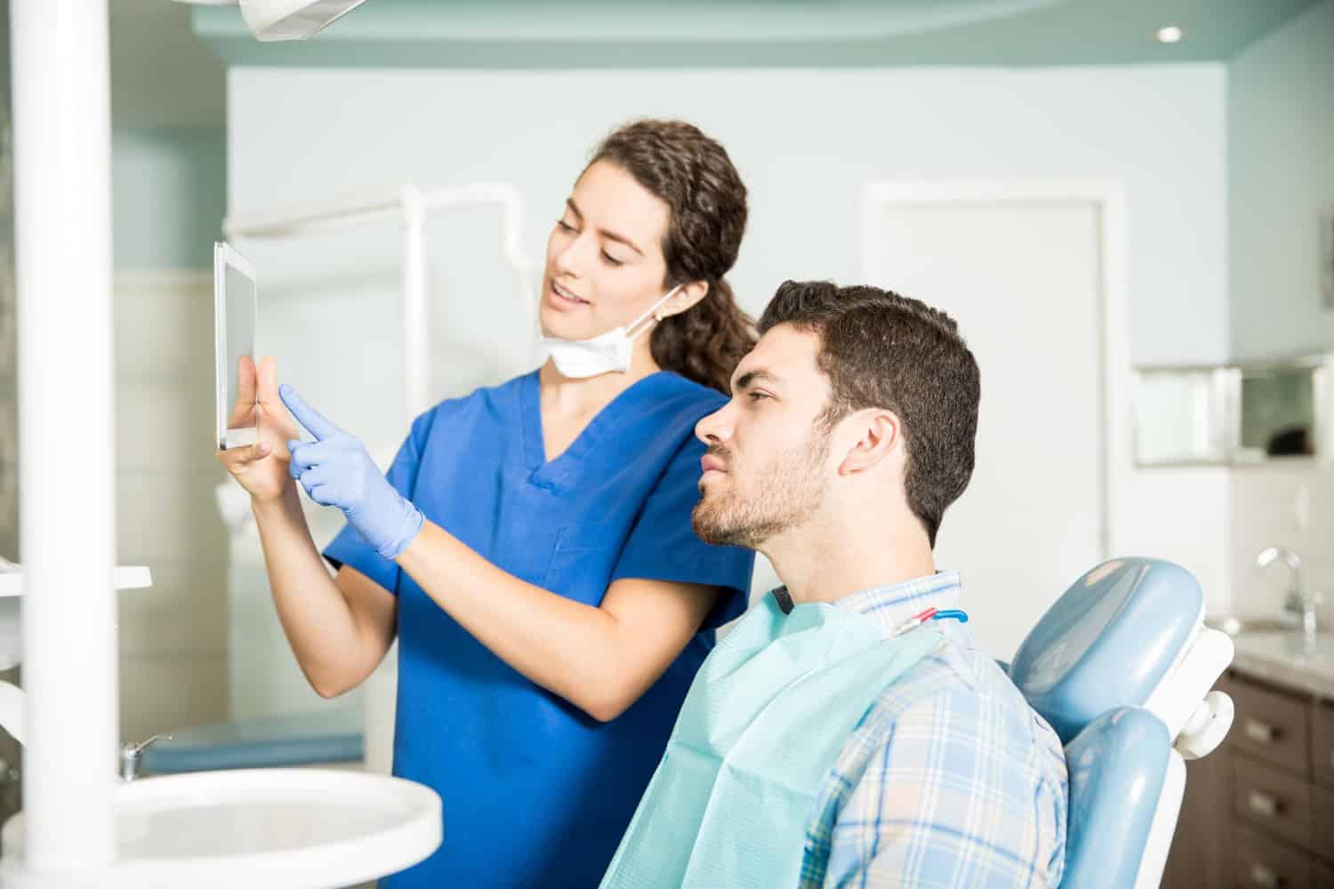 Dentist showing a patient dental X-ray during a treatment consultation.
