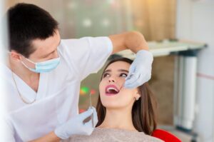 Dentist examining a female patient's teeth during a dental examination.