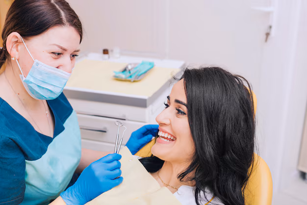 Dentist examining a smiling female patient’s teeth during a dental examination.