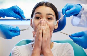 Dental patient experiencing anxiety during a dental examination with dental instruments nearby